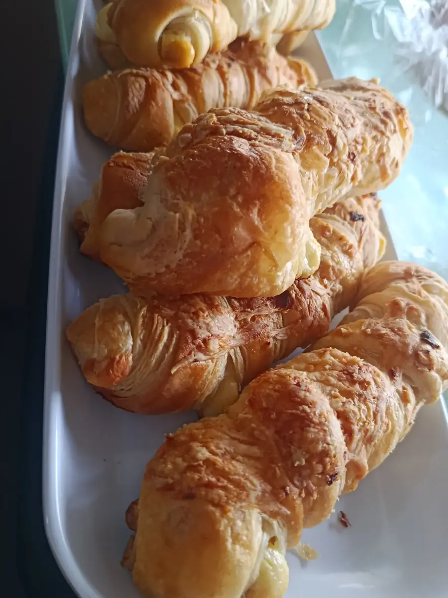 Palitos de queso hojaldrados y croissants en una bandeja