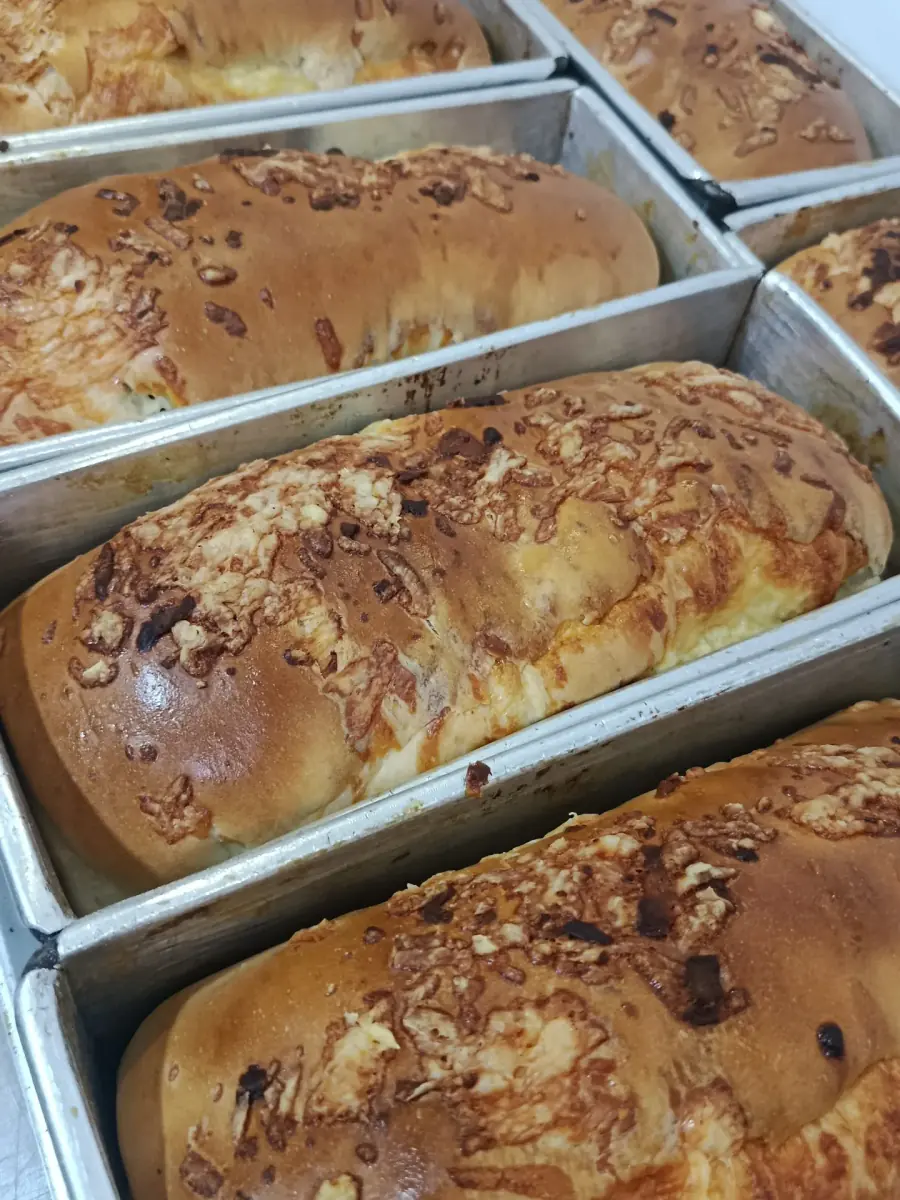 Panes rellenos de queso costeño recién salidos del horno, en sus moldes